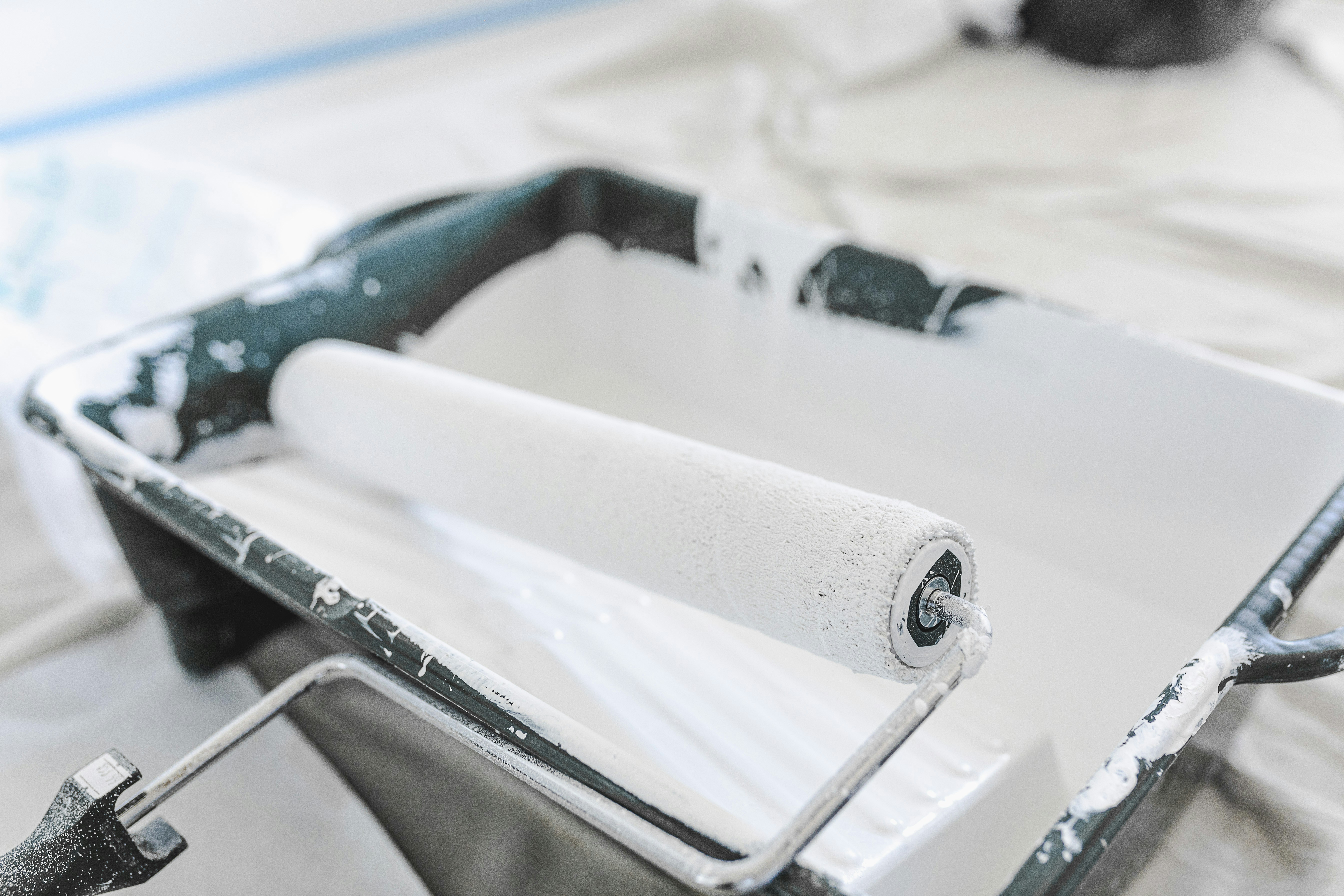 Rouleau de peinture blanche dans un bac de peinture sur un chantier